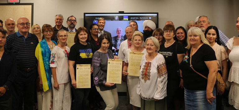 Mayor Keller and Kharkiv Mayor Ihor Terekhov along with other members of Albuquerque’s local Ukrainian community standing in two rows in front of a screen. Individuals in the front are holding printed copies of the intention to establish a Sister Cities International (SCI) relationship with the city of Kharki.