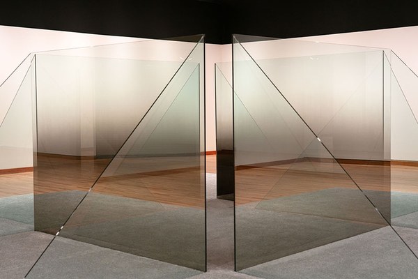 Square and triangular panes of ombre-shaded glass on a carpeted platform such that two triangles support a square as one of four where the square panes are placed at right angles to form an inner square and each square's two triangles serving as support form the perimeter.