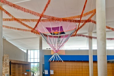 Cannupa Hanska Luger, Unziwoslal wašičuta A view from the side of Unziwoslal wašičuta by Cannupa Hanska Luger, a large-scale, colorful tipi suspended upside-down from the ceiling of the Albuquerque Museum lobby.