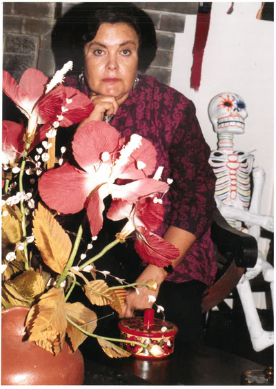 A headshot of artist Catalina Delgado-Trunk, with a red flower and skeleton in frame.