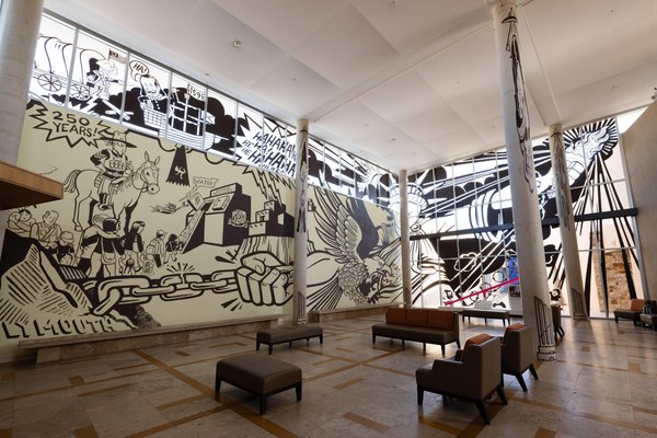A mural on the wall and window of the Albuquerque Museum lobby. On the left is a soldier on horseback watching a line of people walking into an ice box. In the center is the Statue of Liberty in chains. On the right are two children running towards Teeter-Totter Wall (2019) by Ronald Rael, Virginia San Fratello, and Colectivo Chopeke.