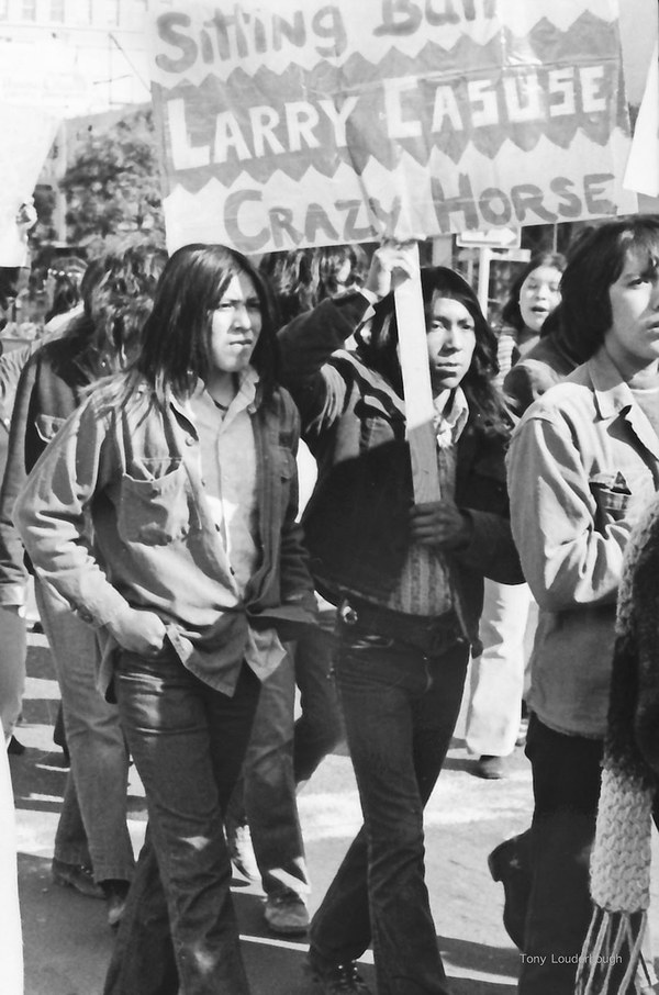 Anthony Louderbough, Demonstrator Holds Sign Reading, “Sitting Bull, Larry Casuse, Crazy Horse” Seven Generations 2020