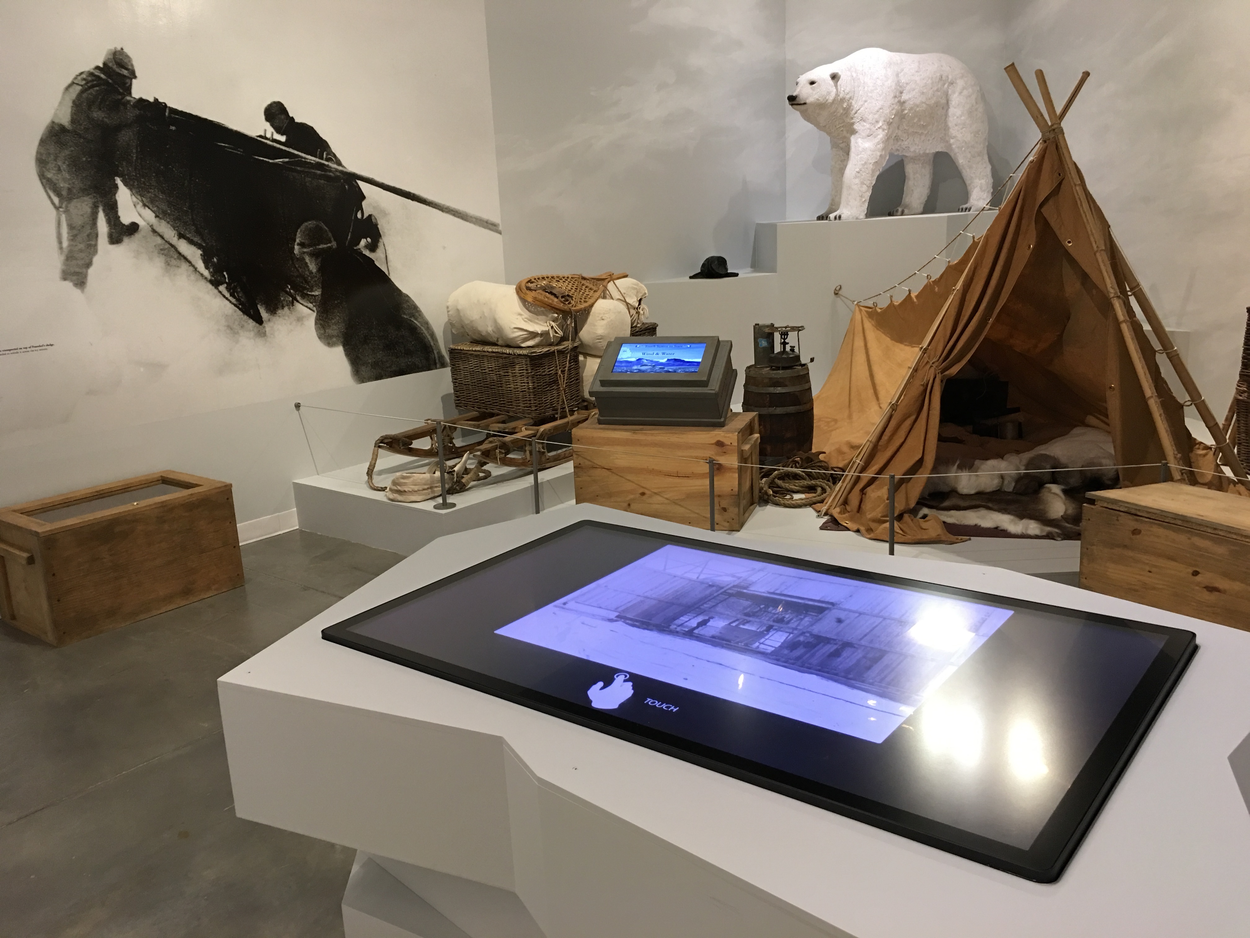 The Arctic Air Camp portion of the exhibition featuring a model display of a camping site. A digital kiosk appears in the foreground.