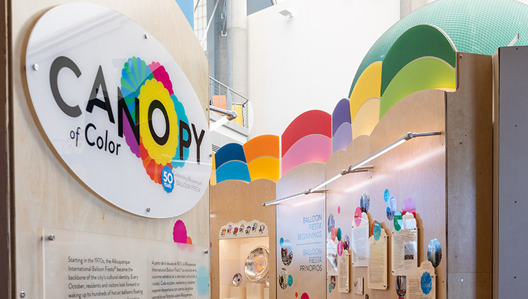 A small section of several displays from the Canopy of Color exhibition, featuring the colorful logo panel with multicolored hot air balloons.