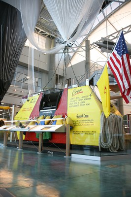 The Double Eagle V exhibit at the Trans-Oceanic & Around the World Flights exhibition at the Albuquerque Balloon Museum. The craft is a yellow and red and the photo is a close-up of the main structure.