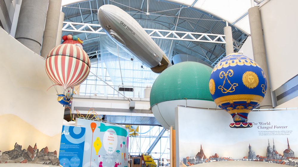 Exterior front of the Balloon Museum with balloons flying over.