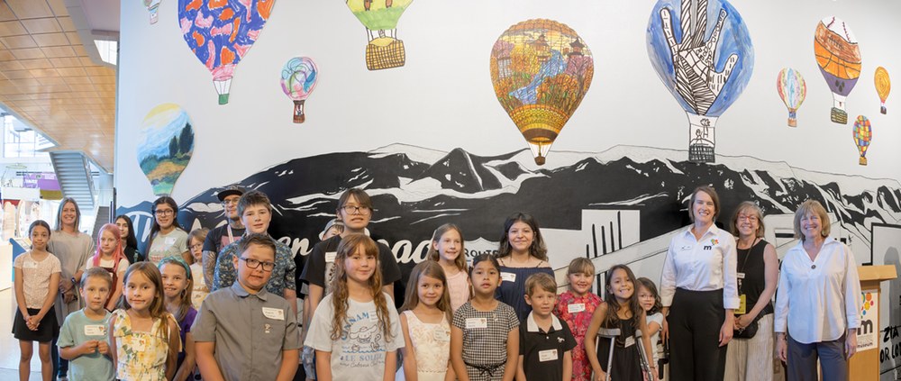 black and white mural of Route 66 with colorful hot air balloon drawings floating above.