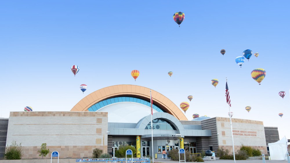 Exterior front of the Balloon Museum with balloons flying over.