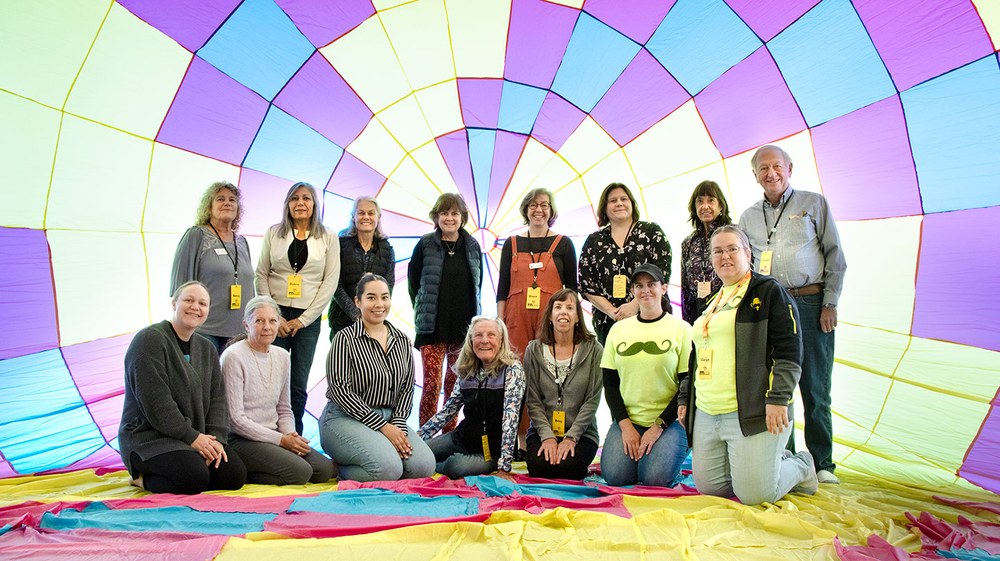 volunteers inside a balloon 2025 A large group of volunteer standing inside a yellow and pink balloon