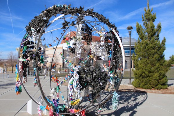 A large, 3D, mixed media artwork featuring a metal ball frame covered with smaller sculptures of various textures and colors.