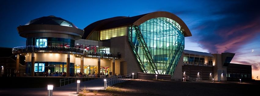 The outside of the balloon museum at night with the lights on.
