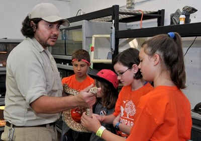 caption:A group of Camp BioPark students meet with a reptile keeper.