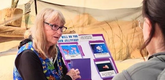 A volunteer explains an educational board to a guest at the Aquarium
