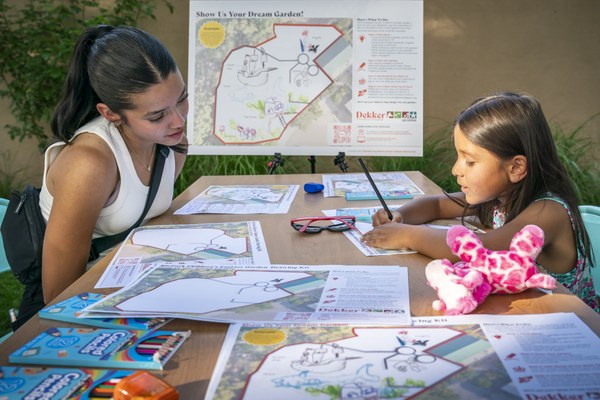 Guests engage at an arts table meant to gather community input on the redesign of the Children's Fantasy Garden, with a map on an easel behind them