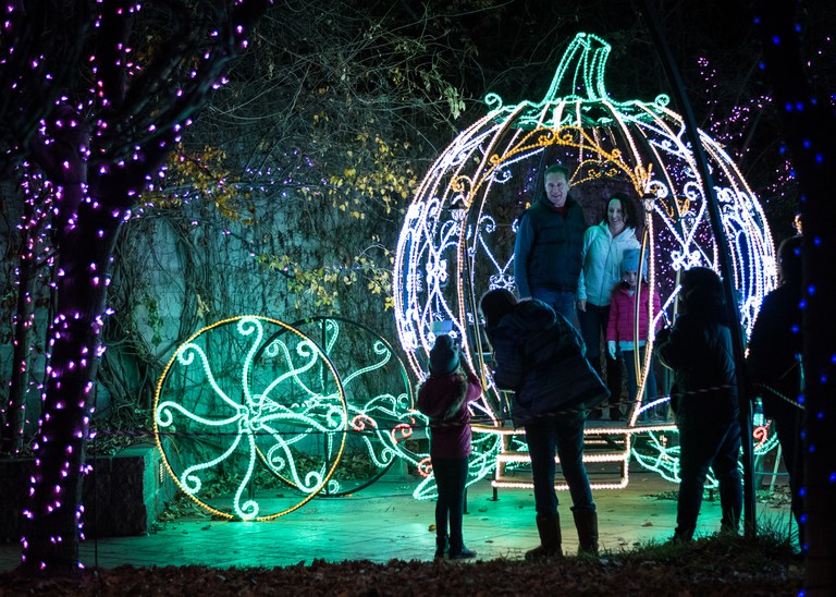 A family takes their photo in the holiday light covered carriage at River of Lights