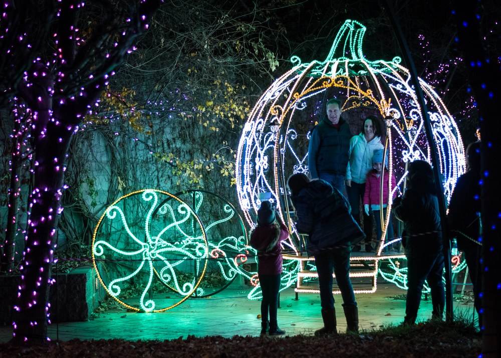 River of Lights Banner 2022 A family takes their photo in the holiday light covered carriage at River of Lights