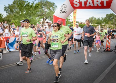 A group of people running away from an inflatable arch the says START.