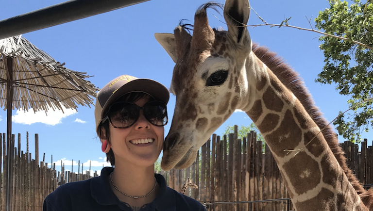 A BioPark staff member poses next to a giraffe.