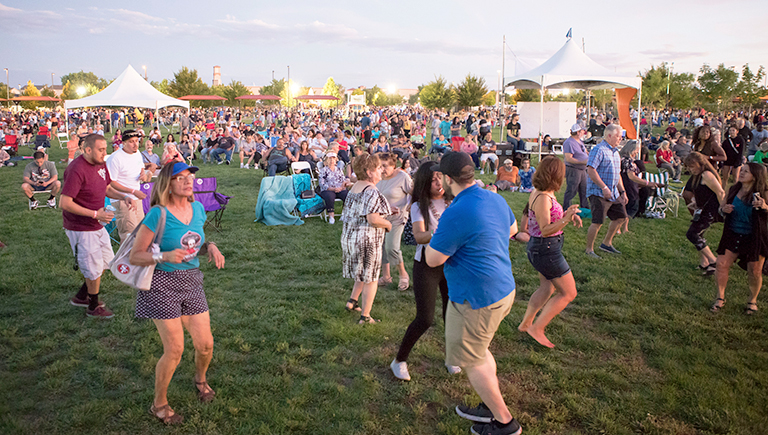 Families dancing in a park at Albuquerque Summerfest.