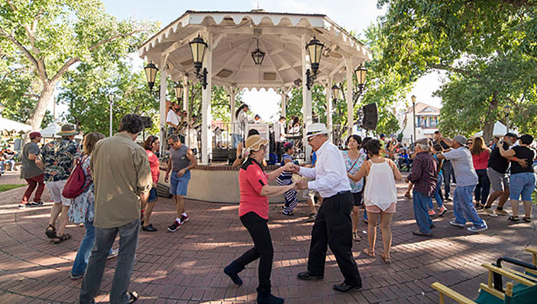 A crowd dancing to live music around the gazebo in History Old Town.