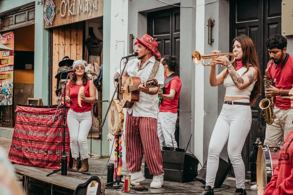 A lively band holding a variety of instruments playing a concert outside on the street.