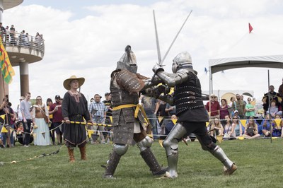 Knights fight on the battlefield as event-goers spectate 