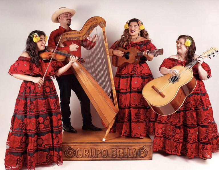 Members of Grupo Bella wear red outfits and pose with their musical instruments.