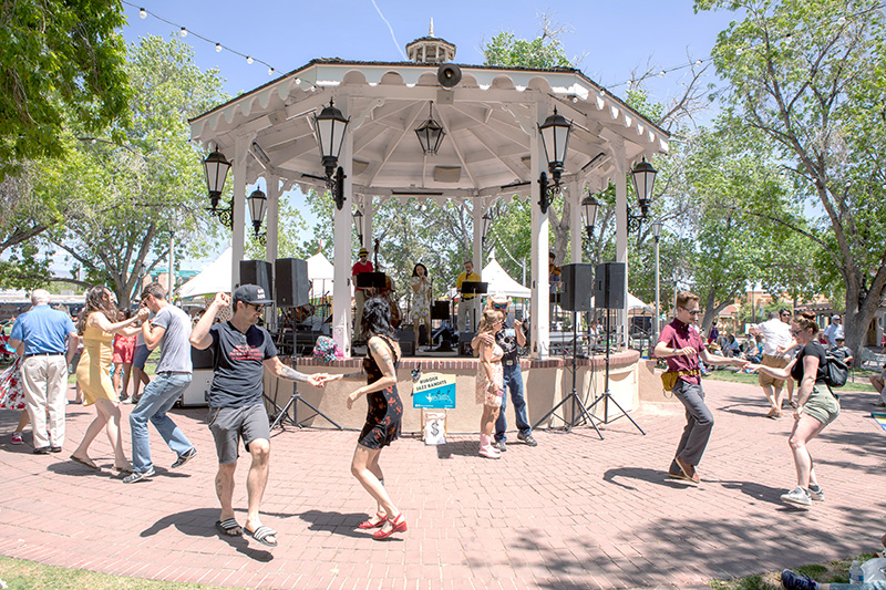Photo of people dancing around the Old Town Gazebo as a band plays on stage.