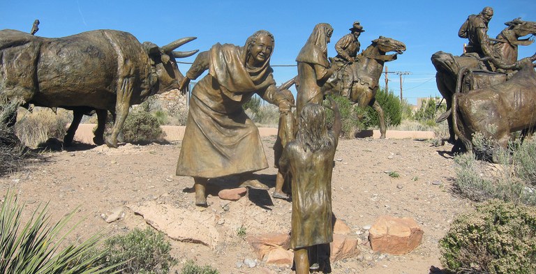A section of the La Jornada sculpture featuring bronze statues of a woman and child in front of various livestock