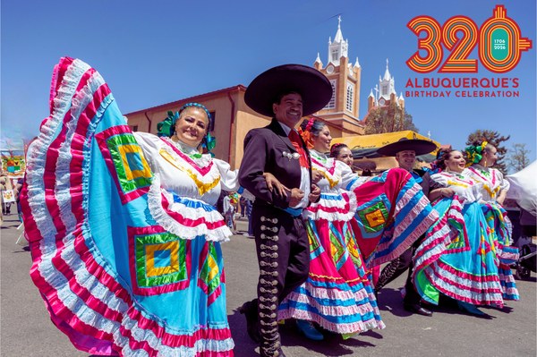 Dancers in colorful traditional Mexican attire perform outdoors during Albuquerque's 320th Birthday Celebration under a clear blue sky.