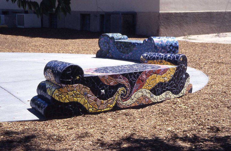 Mosaic benches made with color ceramic tiles depicting spirals, natural forms, and other patterns.