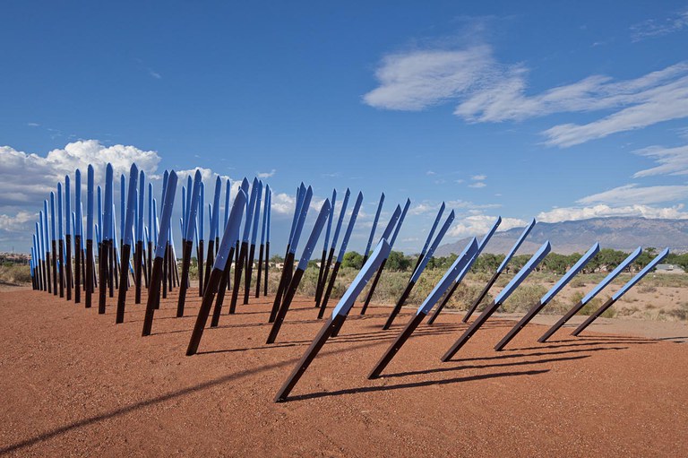 Installation of 100 angle irons with the tops painted blue, arranged as an allussion to birds that inhabit or make seasonal migrations in the Rio Grande Flyway.