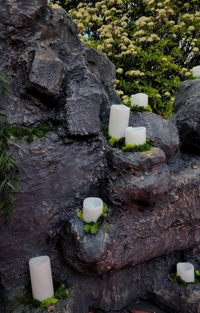 Art installation of carved rocks with candles and foliage.