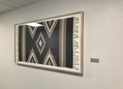Geometric weaving installed horizontally in a light wood frame.