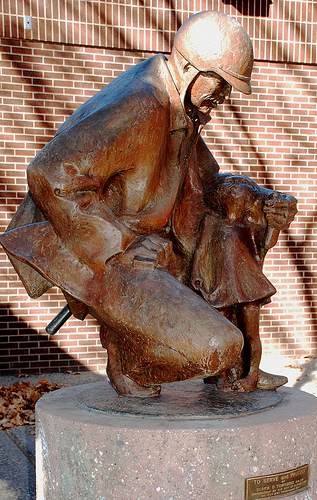 Representative bronze sculpture depicting a public safety figure holding a small child.