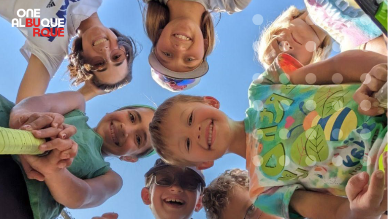 Seven kids standing in a circle looking down toward the camera.