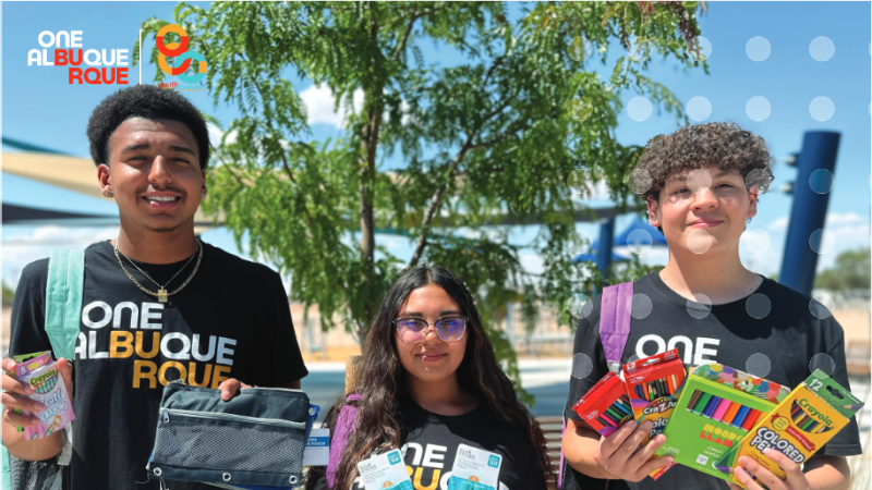 Three teenagers holding school supplies wearing OneAlbuquerque shirts with the yellow writing for Youth and Family.