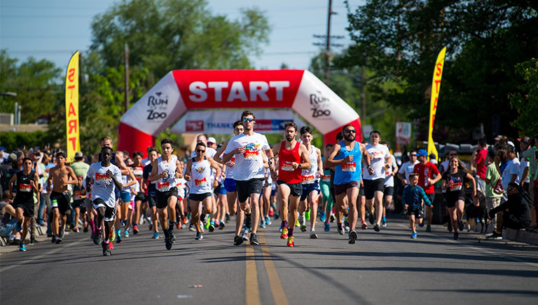 A large group of people running on a street with trees in the background.