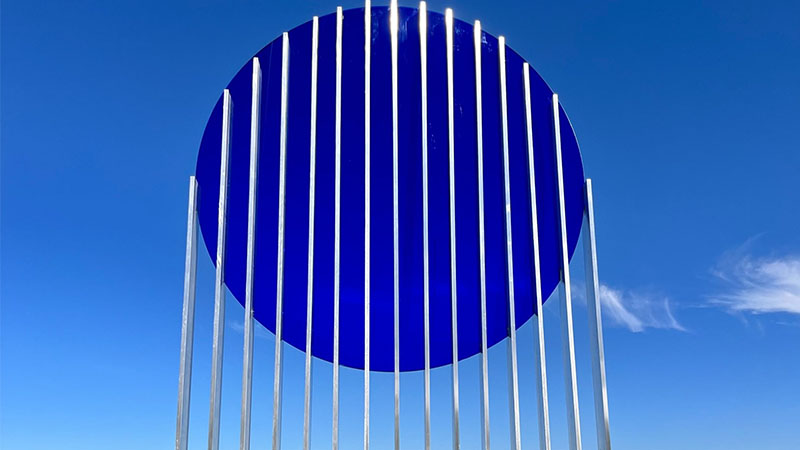 A sculpture for The Art of Annularity exhibition at the Balloon Museum. The sculpture is a large, flat, blue circle suspended in the air by a series of thin metal poles.