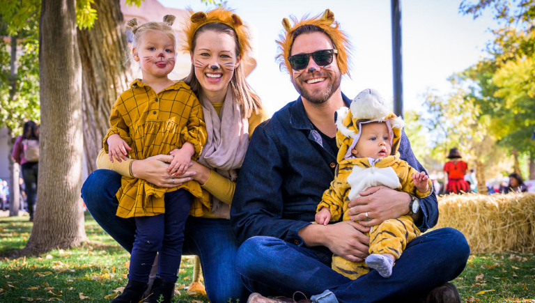 A woman holding a child and a man holding a baby all in tiger costumes.