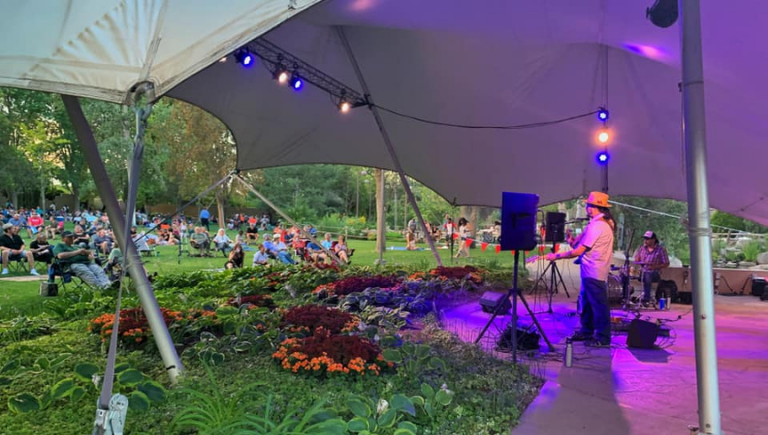 Musicians under the Botanic Garden amphitheater with a crowd in the background.