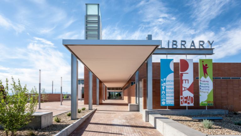 The entrance to the Central & Unser Library with banners with the words: Read, Grow, Think, Enjoy, Talking, Writing, Singing, and Every Child Ready to Read.