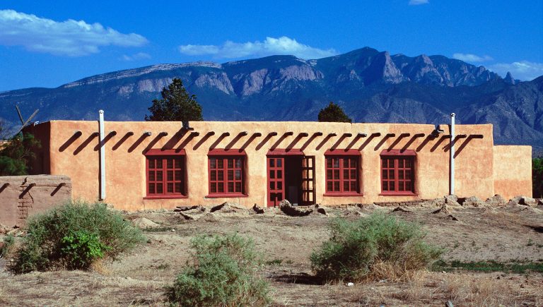 A stucco building in front of the Sandia Mountains.