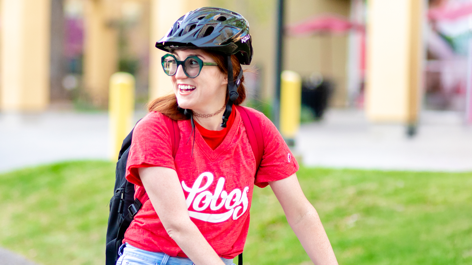 Image of a student wearing a bike helmet and red UNM Lobos t-shirt.