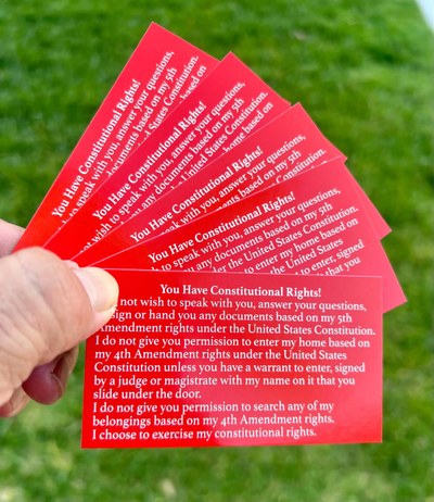 Know Your Rights Red Cards A hand holding red business cards with text in different languages.