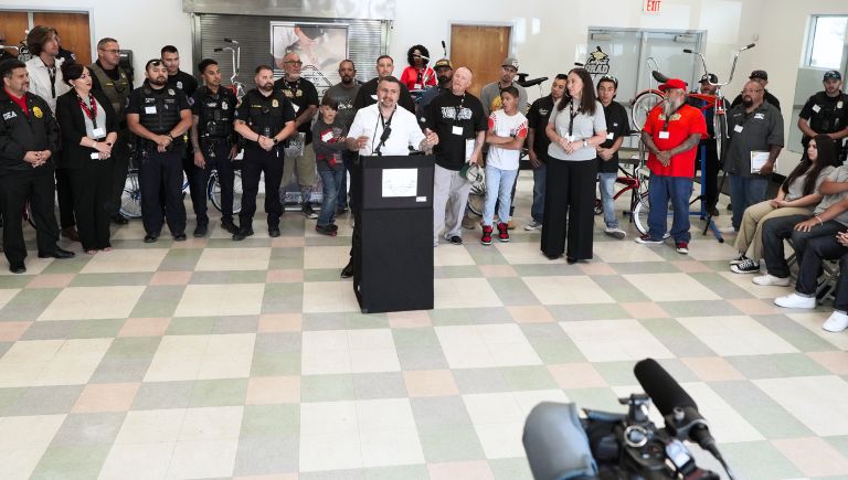 Police officers and people standing around a podium.