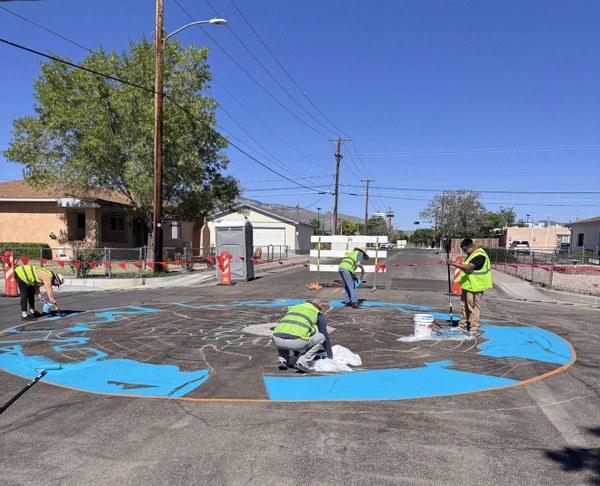 Workers install asphalt murals in an intersection as part of Albuquerque's  International District Choice Neighborhoods Initiative