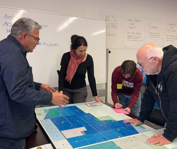 Photo depicts four Albuquerque City Council District 6 constituents working together on a project proposal for the district.