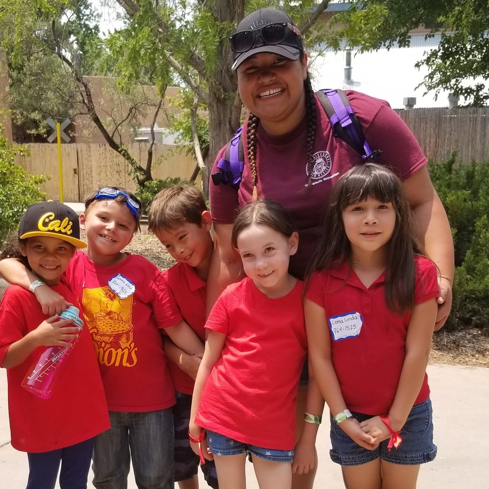 Staff with several children smiling for an outdoor activity