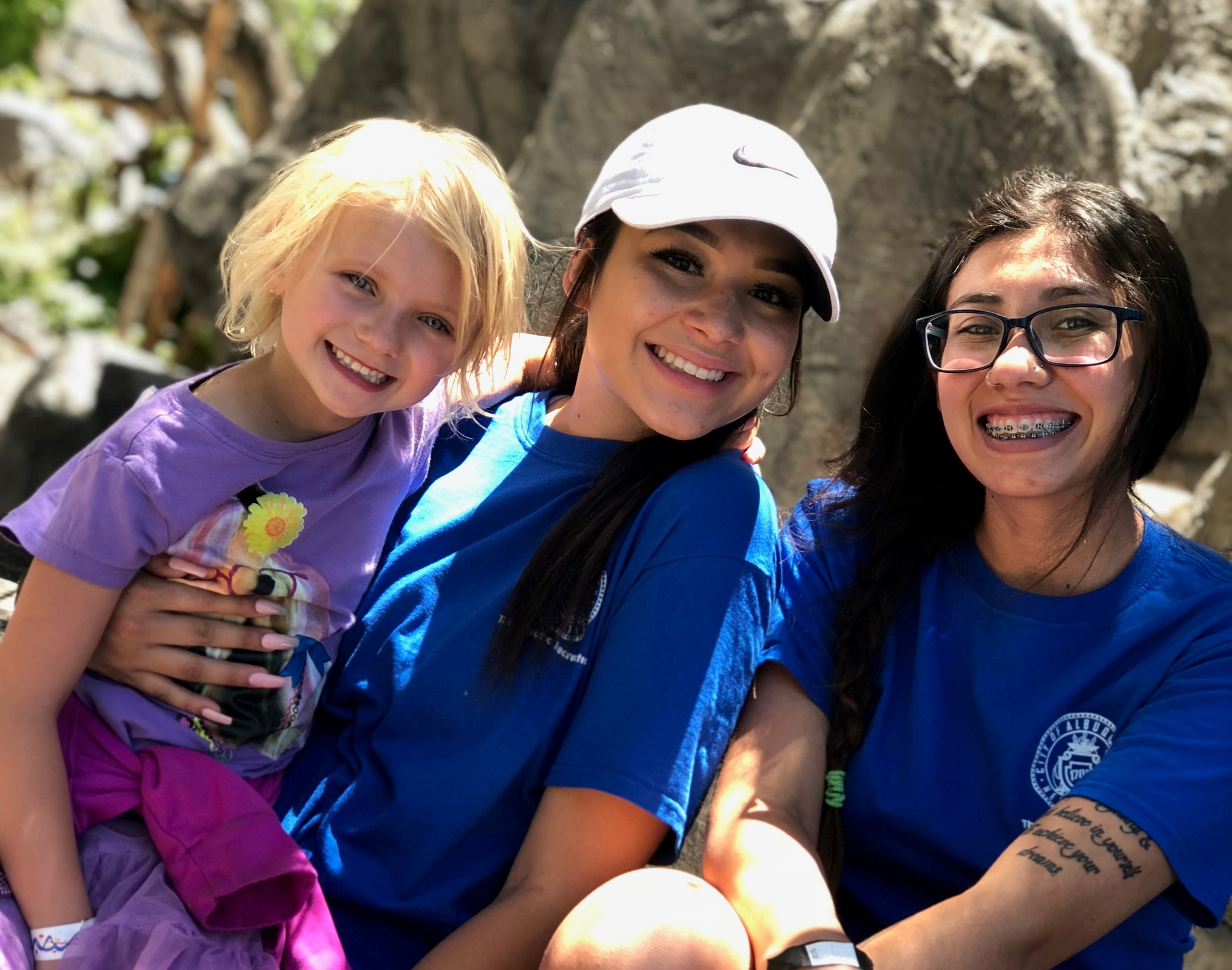 two staff with child smiling outside